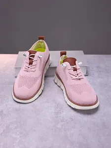 Close-up of pink breathable knitted sneakers with brown leather accents and thick white soles