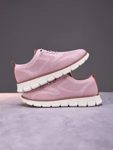 Detail of pink breathable fly-knit fabric and white thick anti-slip sole on casual sneakers