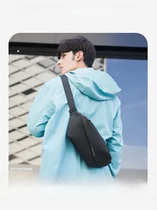Rear view of a man wearing a sleek black waterproof crossbody chest bag in an urban setting