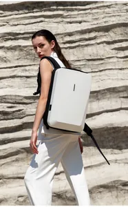 Outdoor shot of a sleek white hard shell laptop backpack on a model by a rock wall