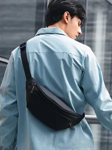 Minimalist black waterproof crossbody chest bag with orange accents shown on model's back