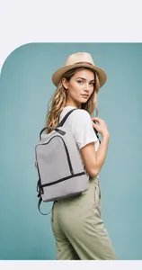 Outdoor lifestyle shot of a gray minimalist casual backpack with black zippers