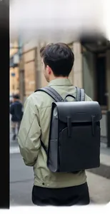 Urban lifestyle shot of a minimalist black waterproof backpack with matte flap cover