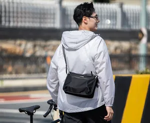 Water-resistant black oxford cloth messenger bag detail worn by cyclist outdoors