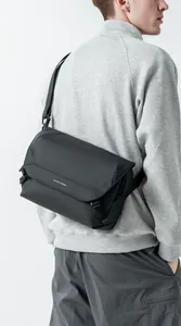 Side view of Mark Ryden black messenger bag on model showing large capacity and strap