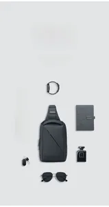 Deep grey sling bag shown with gadgets like smartphone and watch for storage scale