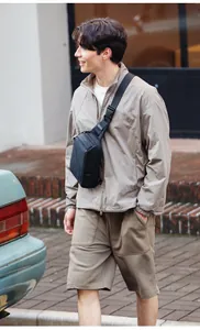 Outdoor street view of a man wearing a black waterproof crossbody bag with geometric design