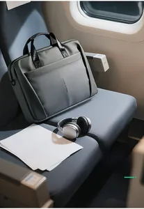 Détail de la sacoche d'ordinateur grise étanche sur siège d'avion montrant les poches
