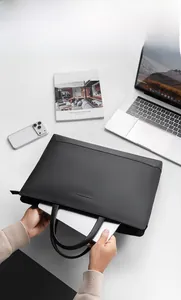 Top view of sleek black 15.6 inch laptop bag on office desk with Kinfolk magazine