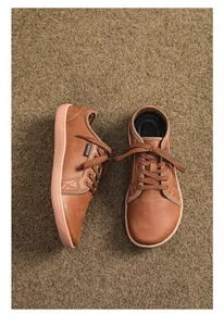 Dettaglio di scarpe a piedi nudi in pelle marrone con etichetta fashion e suola in gomma