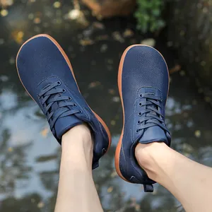 Top-down view of navy blue mesh barefoot shoes with wide toe box on a bright waterfront
