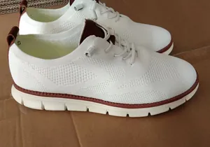 Detail of white flyknit casual loafer showing breathable mesh and brown leather accents
