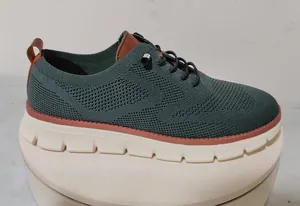 Detail view of breathable dark green knit fabric and brown leather accents on men's loafers