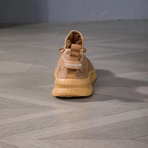 Detail of tan knitted sneaker heel with rubber logo tag on anti-slip wavy sole