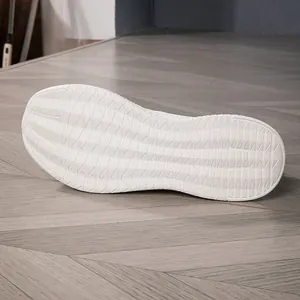 Close-up of white breathable sneakers showing anti-slip wavy texture on the outsole