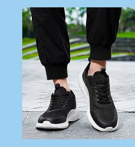 Chaussures de course noires en maille respirante portées à l'extérieur avec semelle épaisse