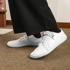 Sneaker minimalista in pelle bianca a piedi nudi con etichetta fashion e suola piatta