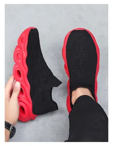 Detail of black knit slip-on sneakers with thick wave-shaped red cushioned soles