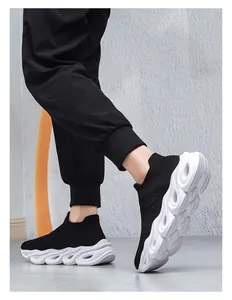 Detailed side view of breathable black knit slip-on sneakers with wavy white platform sole