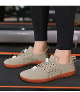 Dettaglio delle scarpe da corsa a piedi nudi kaki con suola arancione su tapis roulant