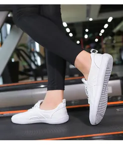 Scarpe da corsa a piedi nudi bianche sul tapis roulant che mostrano la suola antiscivolo
