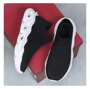 Close-up of black knitted slip-on sneakers with white thick wavy textured outsoles