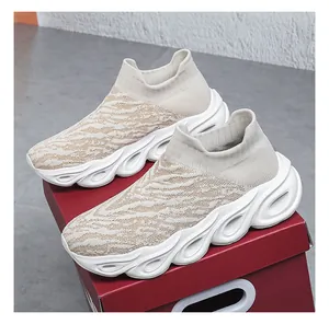 Detailed view of beige knit slip-on sneakers on shoe box with thick wavy sole design