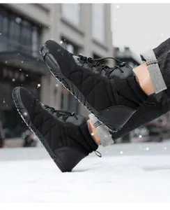 Close-up of black waterproof snow boots with toggle lacing system on snowy ground