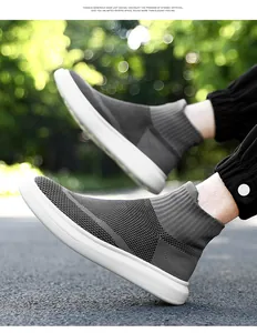 Detail shot of grey knitted sock sneakers with white non-slip sole on asphalt road
