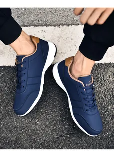 Detail von marineblauen Herren-Sneakern aus Leder mit braunem Fersenpatch auf Asphalt