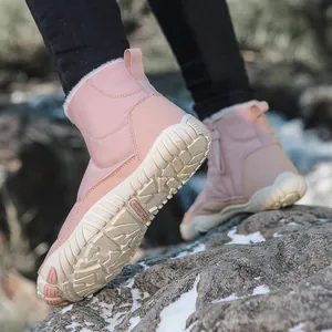 Detail showing non-slip rubber sole of pink snow boots on snow for winter grip