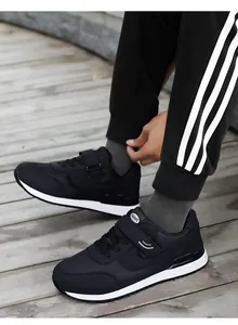 Close-up of black mesh sport shoes with velcro and lace-up closure on wooden floor