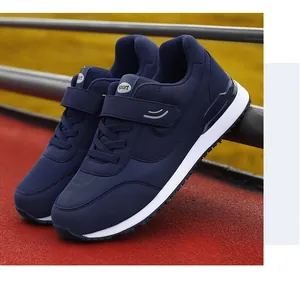 Detail of dark blue walking shoes with velcro straps and non-slip soles on a red track