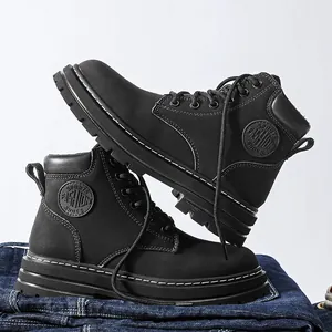 Close-up of black leather work boots with thick soles and contrast stitching on denim