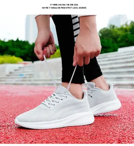 Vue détaillée latérale des chaussures de course en maille gris clair sur piste rouge