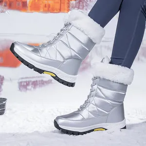 Detail van zilveren waterdichte snowboots met witte voering van imitatiebont in sneeuw