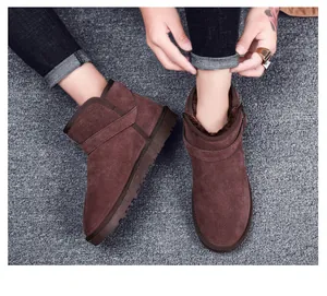 Detail of dark brown leather snow boots featuring thick faux fur lining and buckle strap