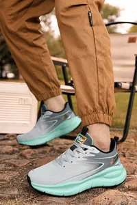 Low-angle outdoor view of grey mesh sneakers with thick mint green shock-absorbing soles