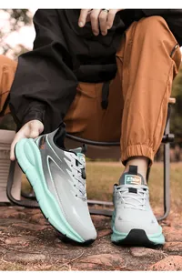 Outdoor shot of men's grey mesh sneakers with green thick sole and orange accents