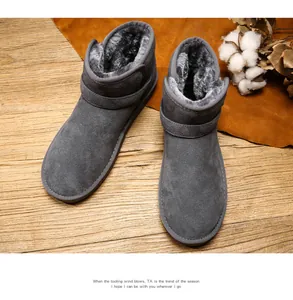 Detail of dark grey leather snow boots with thick plush lining and strap on wood floor