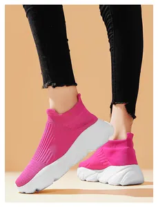 Dettaglio di sneakers a calzino in maglia rosa con suole bianche su una modella