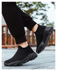 Dettaglio di sneaker in maglia nera con suole spesse antiscivolo su pavimento esterno