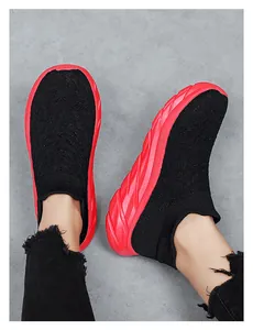 Detail of black knit sock sneakers with chunky red wavy soles on feet