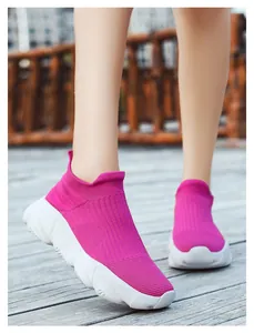 Dettaglio di sneaker in maglia rosa acceso con suola spessa su pedana di legno