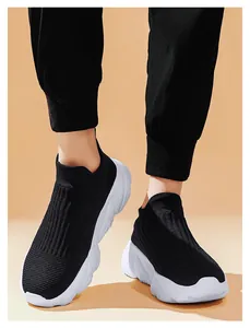 Dettaglio di sneaker in maglia nera con suole bianche spesse indossate dal modello