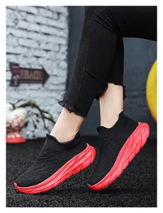Detail of black knit sock sneakers with textured red chunky soles on street background