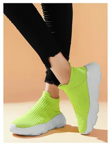 Vista ravvicinata di sneakers a calzino verde fluo con suola a zeppa bianca ondulata