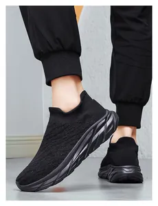 Detail view of black knit sock sneakers showing thick wavy rubber outsole and breathable fabric
