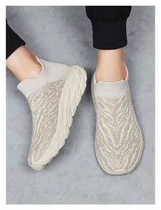 Top-down view of beige knitted platform sock sneakers with wavy texture on grey floor