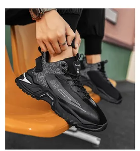Detail eines klobigen schwarzen Sneakers mit Graffiti-Muster und dicker Profilsohle